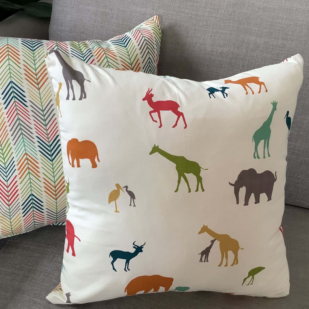 Front and reverse side of out of africa cushion cover on a couch