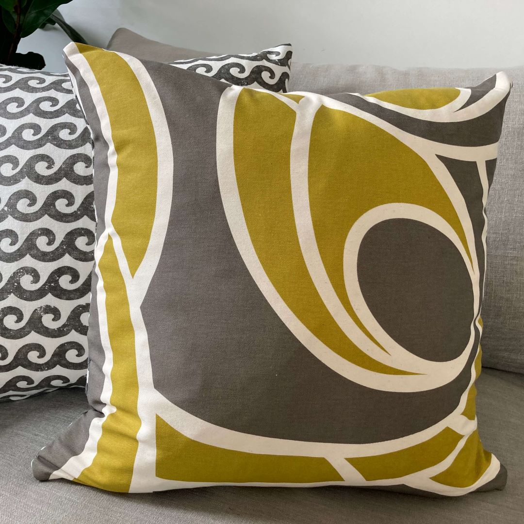 Waves and Swirls cushion covers, showing both sides, on a couch