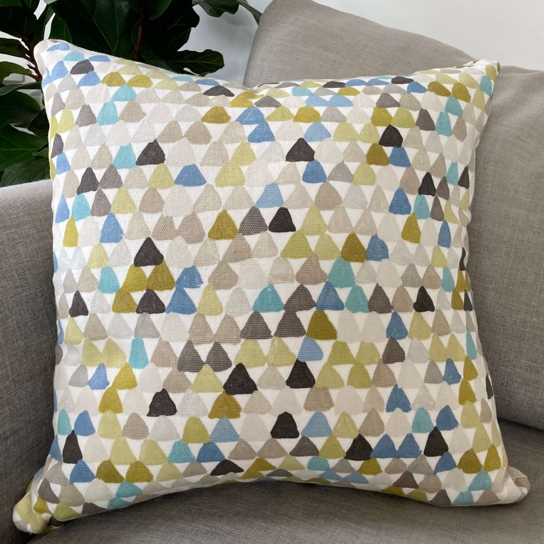 Triangle side of spots and triangles cushion cover on a couch