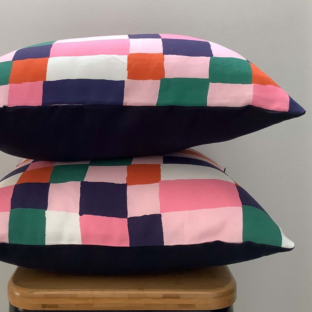 Side view of navy and pink cushion cover showing front in pattern fabric and back in navy linen